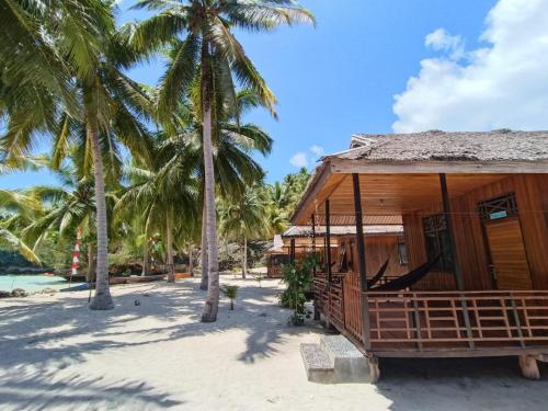 uma casa na praia com palmeiras em Sera Beach Dive Resort em Kododa