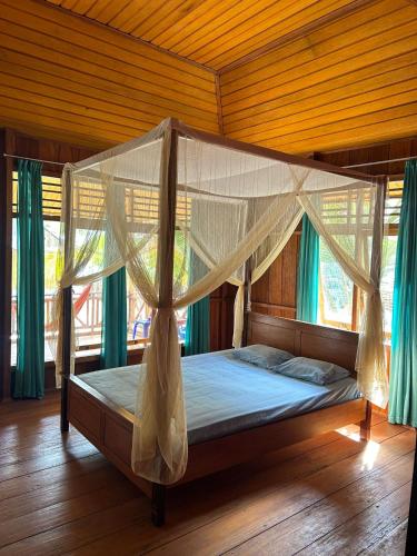 a bed with a canopy in a room with windows at Sera Beach Dive Resort in Kododa