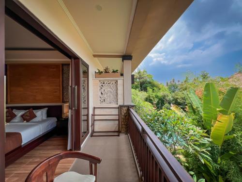 The Mudru Resort by Pramana Villas في أوبود: غرفة نوم مع سرير على شرفة مع اشجار
