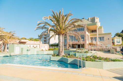 una piscina con palmeras frente a un edificio en Hippocampus resort en Concón