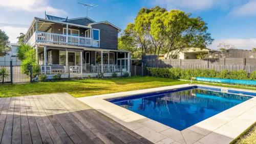 a home with a swimming pool in front of a house at The Birkdale with Heated Pool by Ready Set Stay - BYO Linen and Towels in Sunset Strip