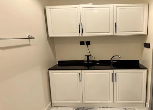 a kitchen with white cabinets and a black counter top at أستديو بدخول ذكي حي الربوة in Riyadh