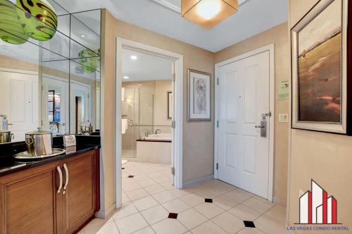 a large bathroom with a sink and a white door at MGM Signature-32-607 F1 Track & Strip View Balcony in Las Vegas