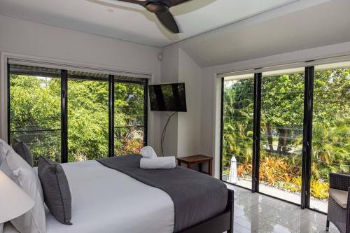 een slaapkamer met een groot bed en grote ramen bij Eden Retreat - Port Douglas in Port Douglas