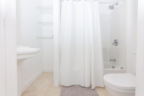 La salle de bains est pourvue d'un rideau de douche blanc et de toilettes. dans l'établissement Home Miami Downtown with Balcony - 5 minutes from Wynwood & Port - Art District near Beach, à Miami