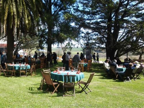 a group of people sitting around tables in the grass at Estancia Turística San Pedro de Timote in Reboledo