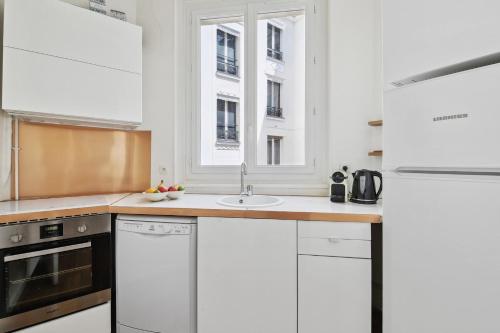 een keuken met witte kasten en een wastafel bij Le Marais & Arts et Métiers - CityApartmentStay in Parijs