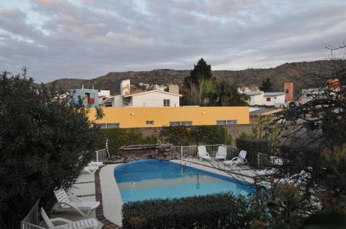 einem Pool mit Stühlen vor einem Gebäude in der Unterkunft Casa Nostra Hotel in Villa Carlos Paz