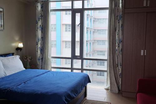 een slaapkamer met een blauw bed en een groot raam bij Condo Suite at 150 Newport near NAIA T3 in Manilla