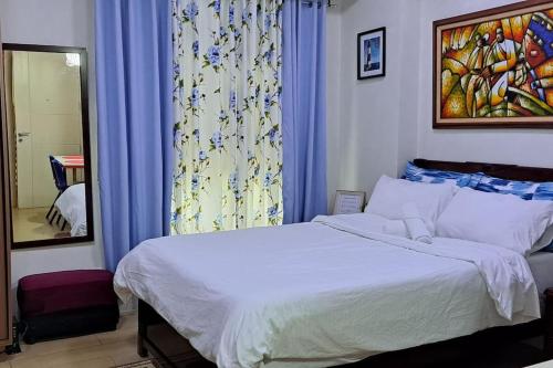 een slaapkamer met een bed en een raam met blauwe gordijnen bij Condo Suite at 150 Newport near NAIA T3 in Manilla