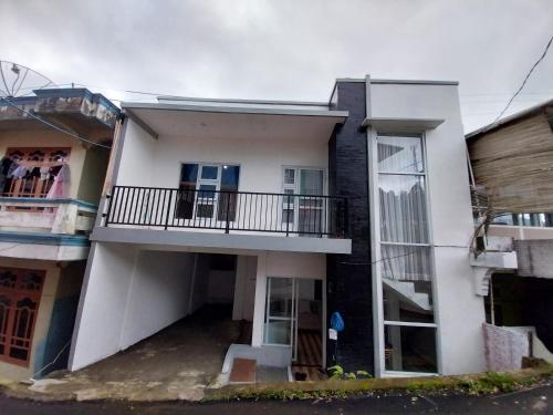 a white house with a balcony on a street at Villa kumudini's in Dieng