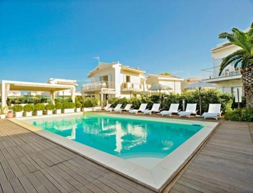 a swimming pool with chairs and a house at Ancora Bianca Beach Residence in Terme Vigliatore