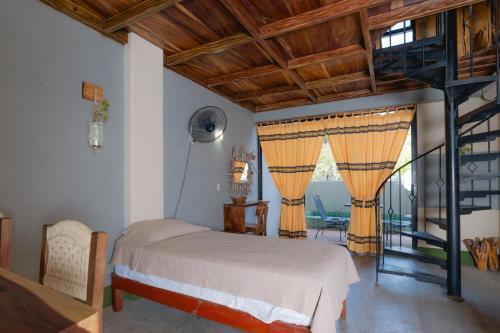a bedroom with a bed and a spiral staircase at Nopalero Suites Hostel in Puerto Escondido