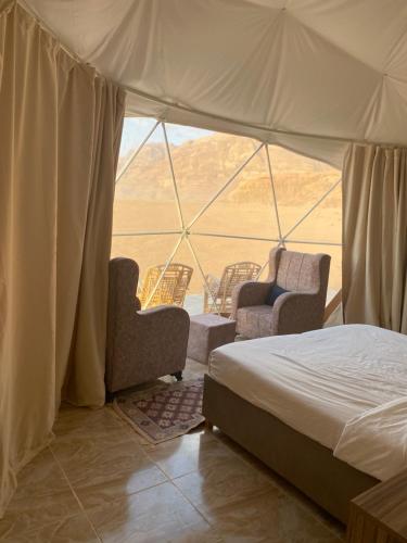 a bedroom with a bed and chairs in a tent at Moon Rum Camp in Wadi Rum