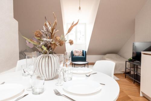 a dining room with a table with white plates and a vase with flowers at 2ndhomes Ullanlinna Penthouse Apartments in Helsinki