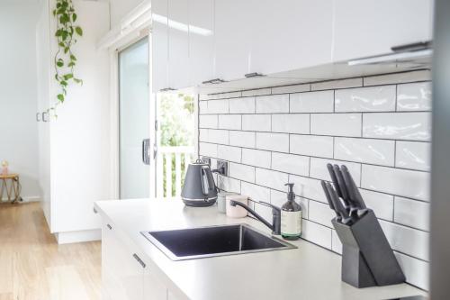 a kitchen with a sink and a white tile wall at Charming Highton Hideaway between CBD and Surf Coast in Geelong