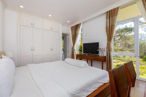 a bedroom with a large white bed and a window at Biệt Thự Lan Anh Đà Lạt in Da Lat