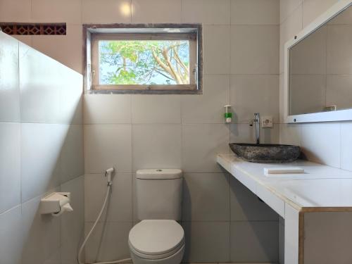 a bathroom with a toilet and a sink and a window at Alam Cottage Uluwatu in Uluwatu