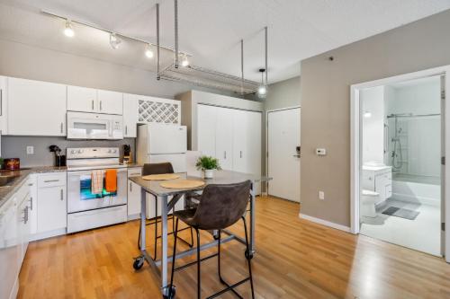 a kitchen with white cabinets and a table with a chair at CozySuites Mill District pool gym # 11 in Minneapolis