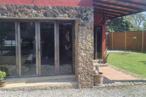 a glass door of a house with a stone wall at Casa-huate Malinalco zona centro ¡disfruta! in Malinalco