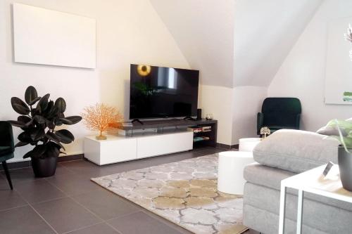 een woonkamer met een flatscreen-tv op een tv-stand bij Modernes, zentrales Apartment in Troisdorf, Region Köln Bonn, maximal für 4 Personen, Parkplatz & Netflix inklusive in Troisdorf