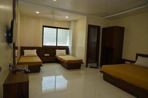 Habitación de hotel con 2 camas y TV en RS GUEST HOUSE en Nagpur