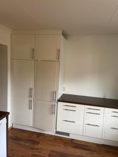 an empty kitchen with white cabinets and a counter at Tingsgatan 24 in Årjäng