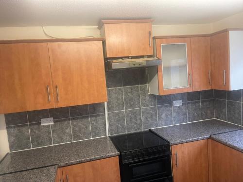 a kitchen with wooden cabinets and a black stove at ODF foundation apartments in Strood