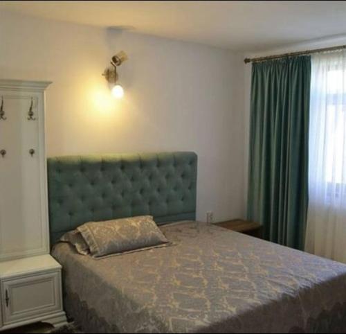 a bedroom with a bed with a blue headboard and a window at Lotca lu Vasile in Crisan