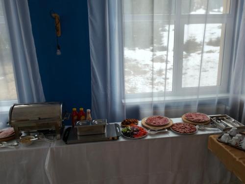 a table with plates of food and a window at Pensiunea Cabana Art in Arieşeni
