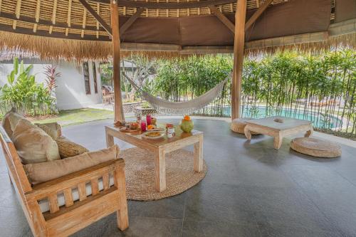 a living room with a hammock and a couch and tables at Oasis Bungalows in Uluwatu