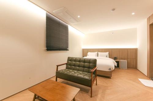 ein Schlafzimmer mit einem Bett, einem Sofa und einem Stuhl in der Unterkunft Hound Hotel Jeonju Deokjin in Jeonju