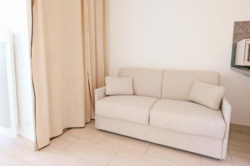 un canapé blanc dans un salon à côté d'une fenêtre dans l'établissement Studio de l'Ilha - Welkeys, à La Grande Motte