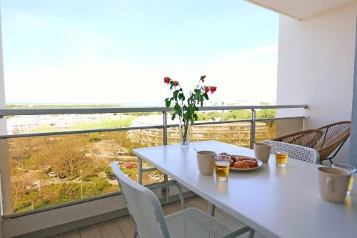 - une table et des chaises blanches dans une chambre dotée d'une grande fenêtre dans l'établissement Studio de l'Ilha - Welkeys, à La Grande Motte