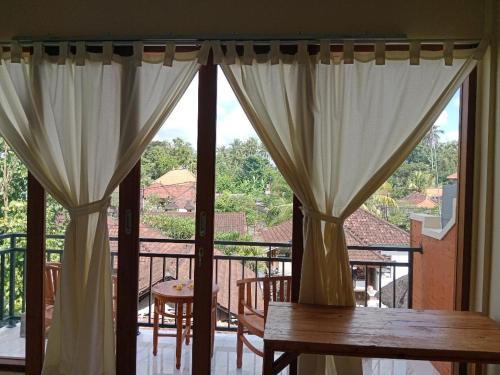 a balcony with curtains and a table and chairs at INJIHAR HOUSE in Ubud