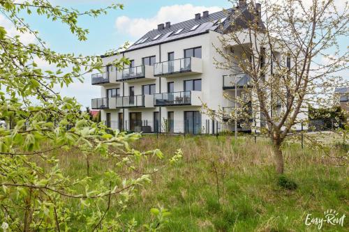 an apartment building on a hill with grass at Dwupoziomowy apartament Grande in Rewal