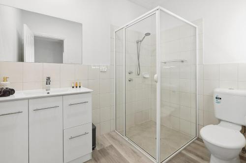 uma casa de banho branca com um chuveiro e um WC. em Shamrock House C em Renmark