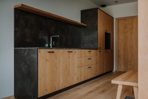 een keuken met houten kasten en een zwarte muur bij Stollhof - New 2024 in Lagundo