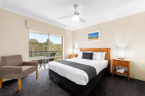 a bedroom with a bed and a chair and a balcony at Tamarind Sands Resort in Cabarita Beach