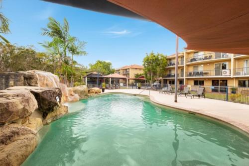 a swimming pool with a waterfall in a resort at Tamarind Sands Resort in Cabarita Beach