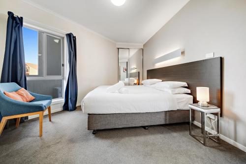 sypialnia z dużym łóżkiem i niebieskim krzesłem w obiekcie Comfy Lakeside 1-Bed with Secure Parking w mieście Tuggeranong