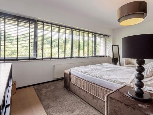 Schlafzimmer mit einem Bett und großen Fenstern in der Unterkunft Wellness villa on the water near Harderwijk in Zeewolde