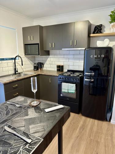 a kitchen with black appliances and a table with a wine glass at Luxe Palm Studio Villa - In the heart of Edge Hill in Edge Hill