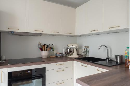 une cuisine avec des armoires blanches et un appareil noir dans l'établissement Pretty cocoon of love close to the City of Light, à Montrouge