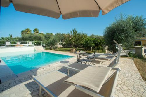 uma piscina com cadeiras, uma mesa e um guarda-sol em Relais il Melograno em Arnesano