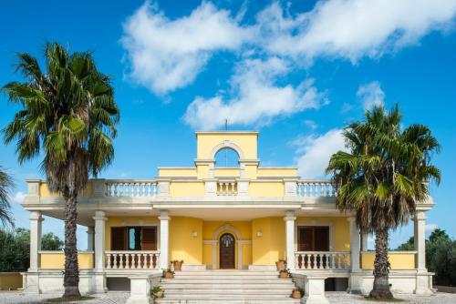 a yellow building with palm trees in front of it at Relais il Melograno in Arnesano