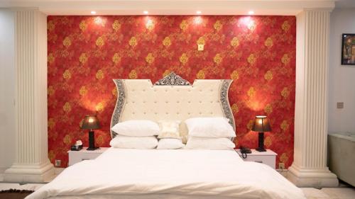 une chambre avec un lit blanc avec un mur rouge dans l'établissement Close, à Islamabad
