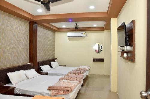 Habitación con 4 camas y TV. en Green leaf Hotel en Ujjain