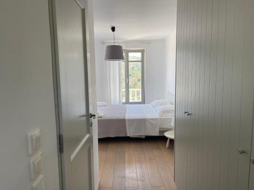 a white bedroom with a bed and a window at AEGEAN WINGS MAISONETTE in Ioulida