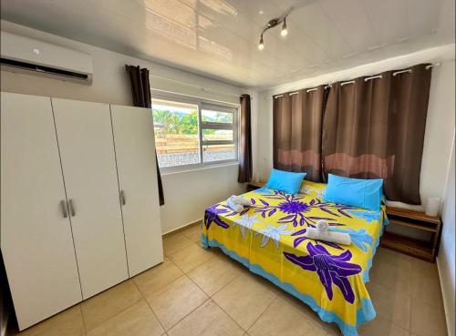 um quarto com uma cama com almofadas azuis em Maison Te Manu - plage privée avec vue sur Tahiti à quelques pas em Maatea